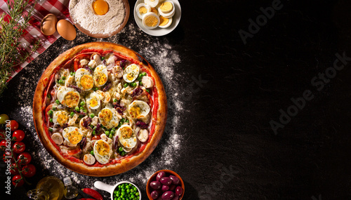Traditional Portuguese Pizza with egg, olive, palm heart and pea. Top view on black concrete background, close up. Traditional Brazilian Pizza