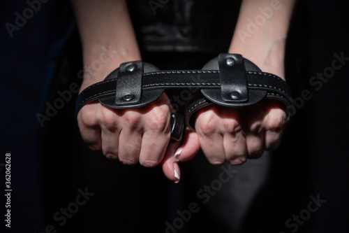 Close-up leather blindfolds in female hands. Unrecognizable woman holds bdsm equipment in the dark. Sexual role-playing games for adults. Humility and dominance.