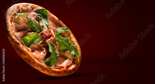 Brazilian pizza with prosciutto and arugula. Side view on red background, close up. Traditional Brazilian Pizza