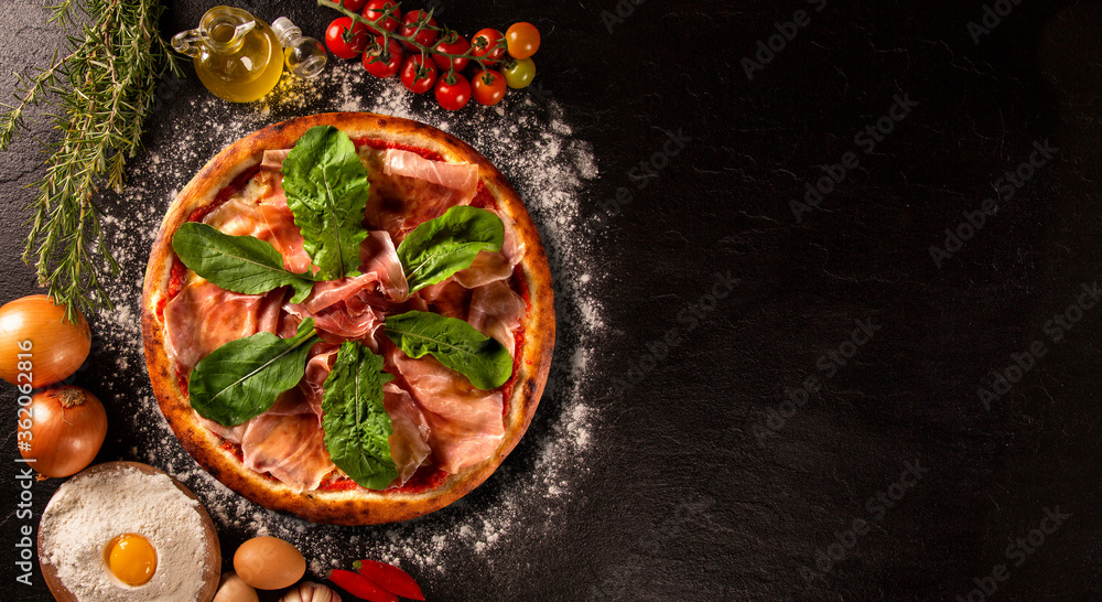 Brazilian pizza with prosciutto and arugula. Top view on black concrete background, close up. Traditional Brazilian Pizza Brazilian pizza with prosciutto and arugula. Top view on black concrete background, close up. Traditional Brazilian Pizza