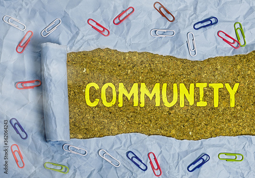 Conceptual hand writing showing Community. Concept meaning group of showing with a common characteristics living together Rolled ripped torn cardboard above a wooden classic table photo