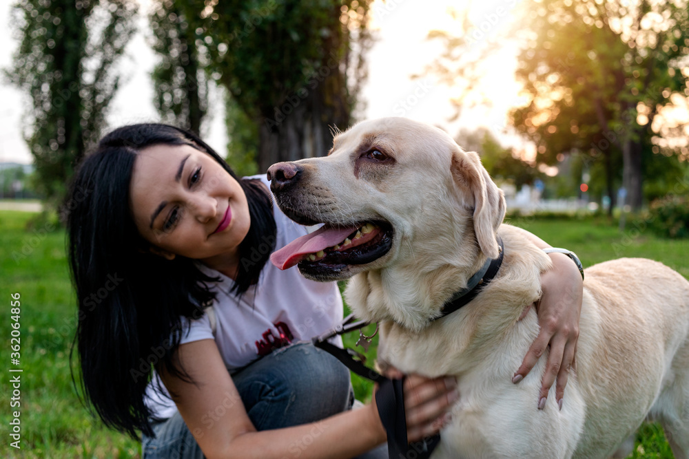 Beautiful young woman enjoying time with her best friend Labrador dog in the park at sunset. Outdoor leisure activity with a pet. Beautiful young woman enjoying time with her best friend Labrador dog in the park at sunset. Outdoor leisure activity with a pet.