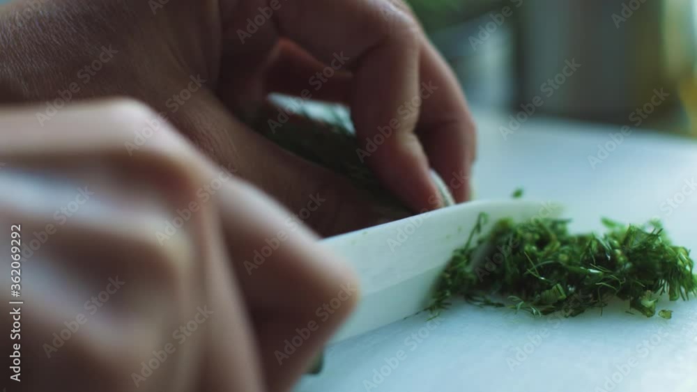 Slicing parsley & dill on a white board, female hands taken from close up in slow motion. ProRES Slicing parsley & dill on a white board, female hands taken from close up in slow motion. ProRES