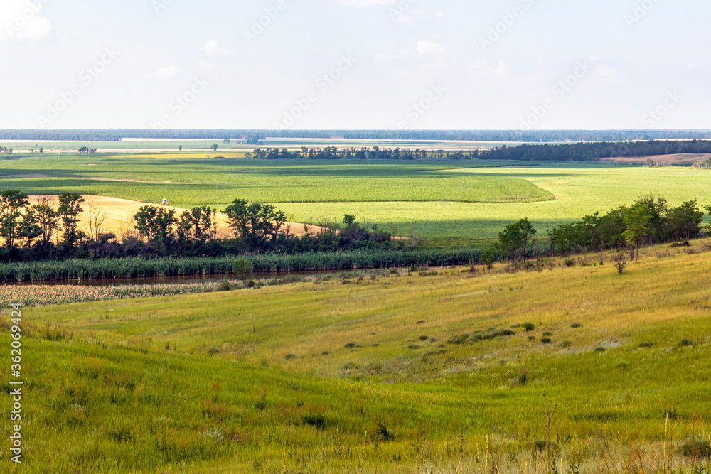View from the hill to the river and agricultural fields to the horizon and blue sky. Russia, Krasnodar Territory.