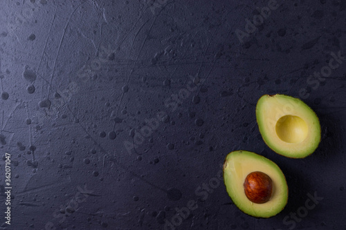 two avocado halves on dark grunge concrete surface