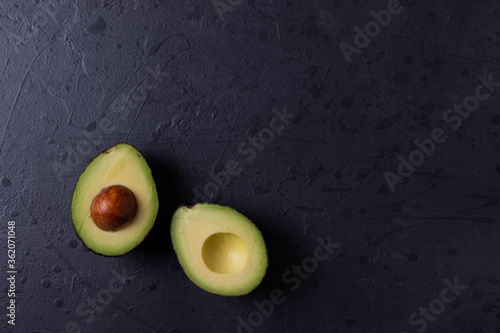 two avocado halves on dark grunge concrete surface