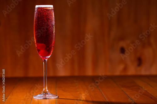Kir royal cocktail with cherry on wood background