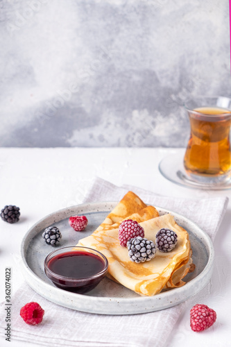 Thin pancakes with frozen berries. Breakfast concept. Text space photo