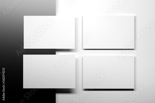 Simple flat arrangement of four blank white business cards on black and white surface