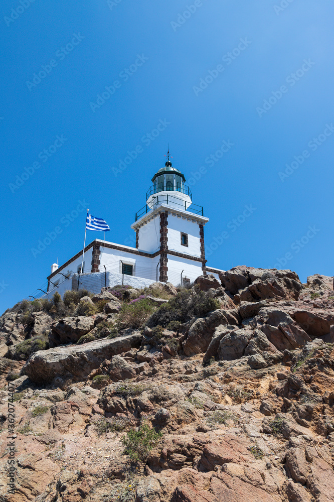At the Akrotiri lighthouse on Santorini island in Greece. The background is a blue sky without clouds.