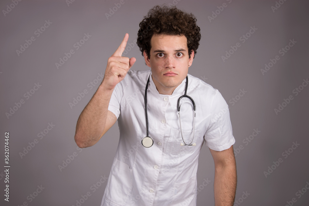 Young male doctor character with stethoscope, studio shot, pointing finger gesture Young male doctor character with stethoscope, studio shot, pointing finger gesture