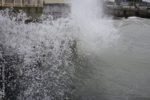 a sea wave breaks on the pier