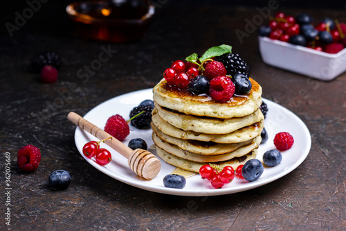Sweet Homemade Pancakes with berries, honey or maple syrup on black background. Morning breakfast concept