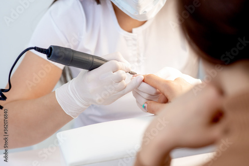 Manicure master uses an electric nail machine to remove nail polish hands in nail salon