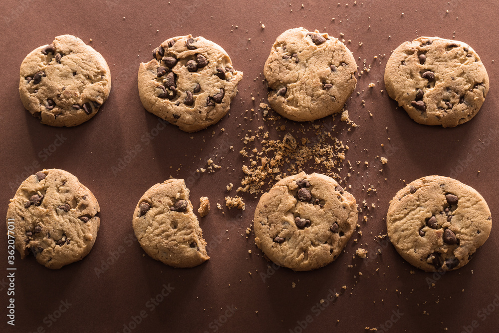 Broken chocolate chip cookies on brown background Broken chocolate chip cookies on brown background