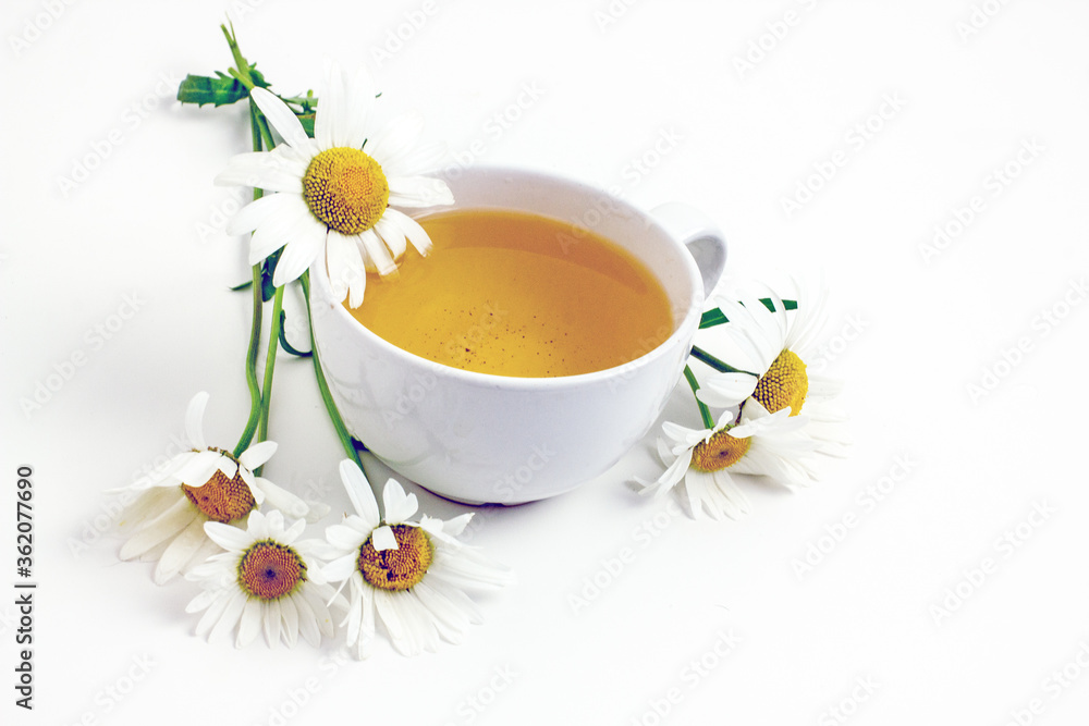 Chamomile tea. Flower tea in a white mug on a white table, near daisy flowers,copy space Chamomile tea. Flower tea in a white mug on a white table, near daisy flowers,copy space