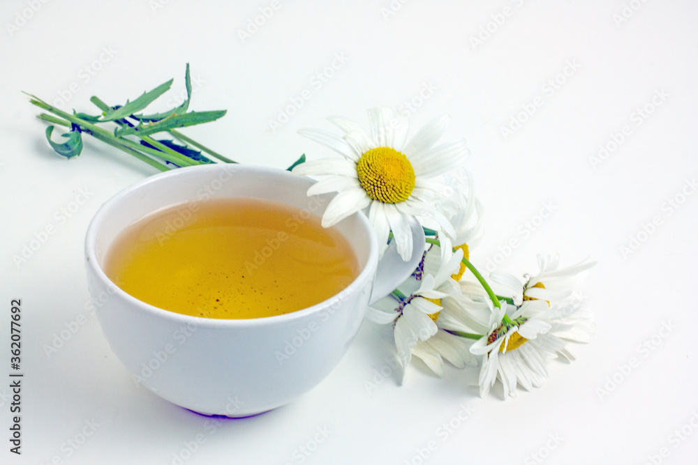 Chamomile tea. Flower tea in a white mug on a white table, near daisy flowers,copy space Chamomile tea. Flower tea in a white mug on a white table, near daisy flowers,copy space