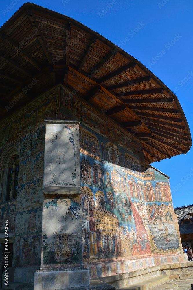VORONET MONASTERY, BUCOVINA, ROMANIA, EUROPE, SPRING 2018. Back of the Orthodox Voronet Monastery with outdoor paintings and portraits of Byzantine-influenced saints. Moldovan architectural style