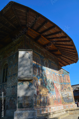 Obraz na płótnie VORONET MONASTERY, BUCOVINA, ROMANIA, EUROPE, SPRING 2018. Back of the Orthodox Voronet Monastery with outdoor paintings and portraits of Byzantine-influenced saints. Moldovan architectural style w salonie