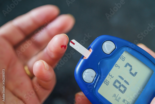 Medicine, Diabetes, Glycemia, Health care and people concept - close up of female using lancelet on finger to checking blood sugar level by Glucose meter photo