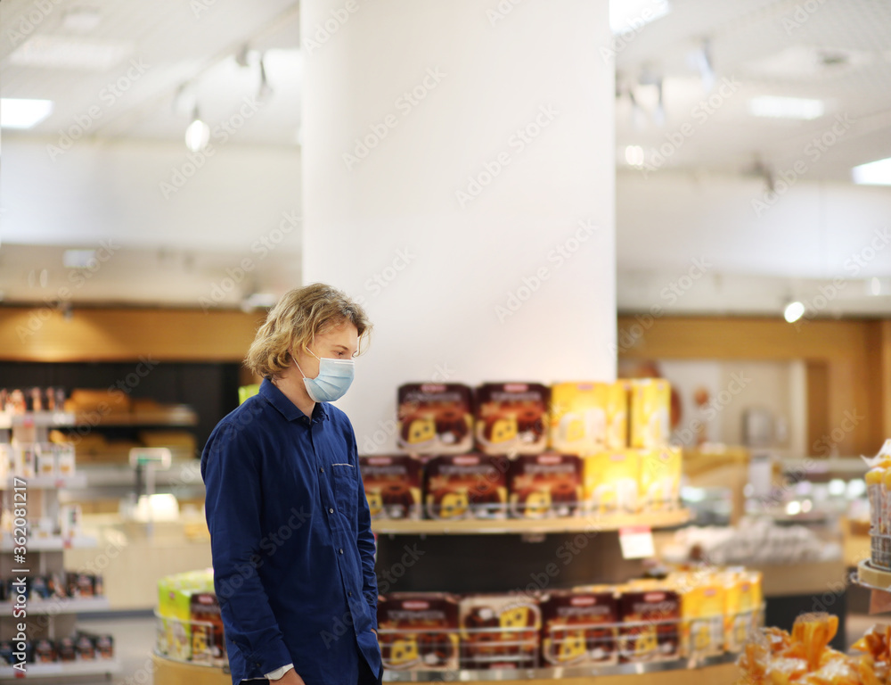 Supermarket shopping, face mask and gloves,Young man shopping in supermarket, reading product information Supermarket shopping, face mask and gloves,Young man shopping in supermarket, reading product information