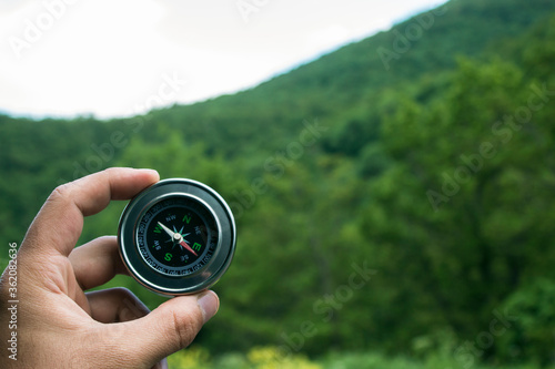 Holds the compass against the background of nature