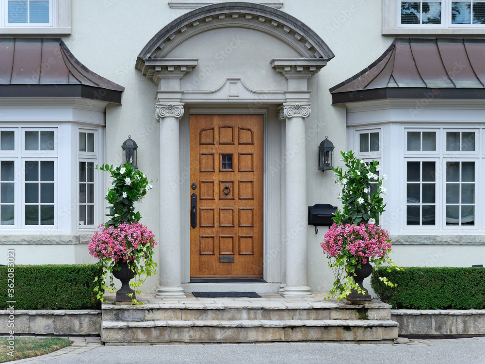 elegant wooden front door of stucco house with portico entrance