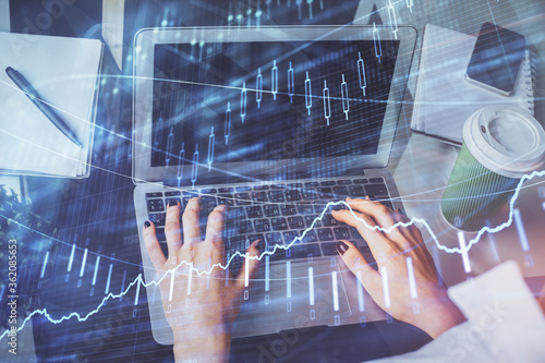 Double exposure of woman hands typing on computer and forex chart hologram drawing. Stock market invest concept.