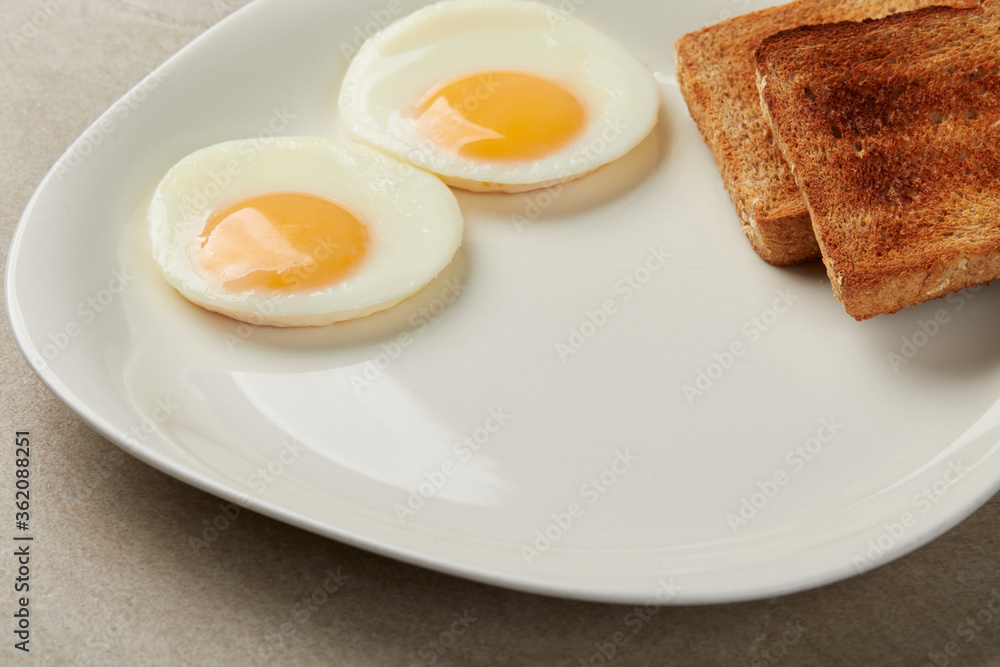 two eggs sunny side up with 2 toasted integral bread on a white plate two eggs sunny side up with 2 toasted integral bread on a white plate