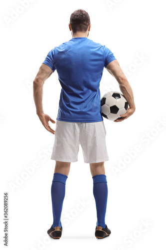 Full length rear shot of a soccer player with a ball under arm
