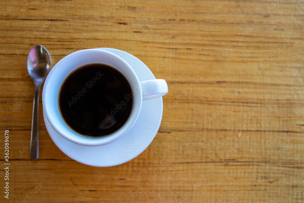 Black coffee in white cup on wooden table. Coffee drinking concept. Coffee cup and spoon top view photo. Black coffee in white cup on wooden table. Coffee drinking concept. Coffee cup and spoon top view photo.