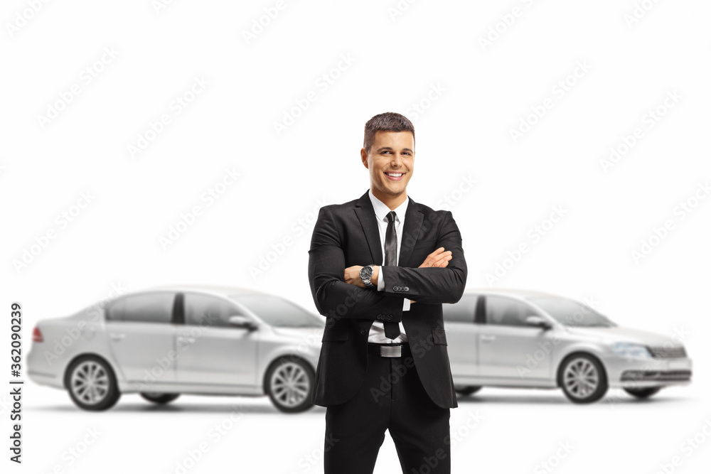 Professional man in a suit posing with crossed arms in a car showroom