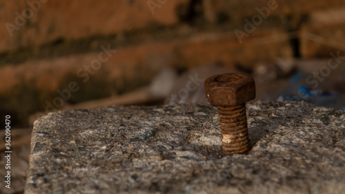 Rusty iron bolts that stick on stones beside the wall