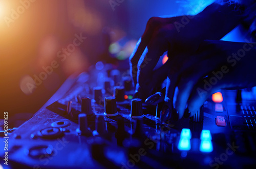 Hand of a DJ girl on the background of a music controller mixer.