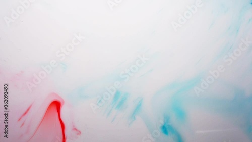 Blue and red color additive dance in white milk, some drops of food coloring in milk with a soap