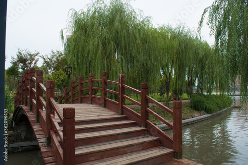 A beautiful view of a lovely park, Jiading, Shanghai, with wooden bridge, willow trees and river in a summer day.  photo