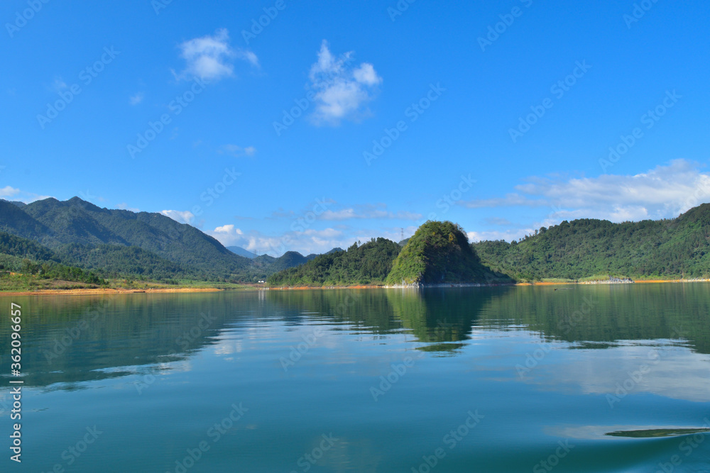 a beautiful lake surrounded by  the mountains in the Summer with white cloud in the blue sky