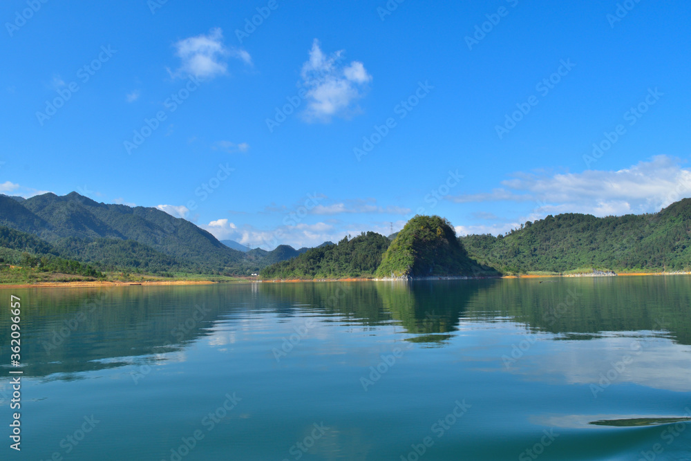 a beautiful lake surrounded by the mountains in the Summer with white cloud in the blue sky a beautiful lake surrounded by the mountains in the Summer with white cloud in the blue sky