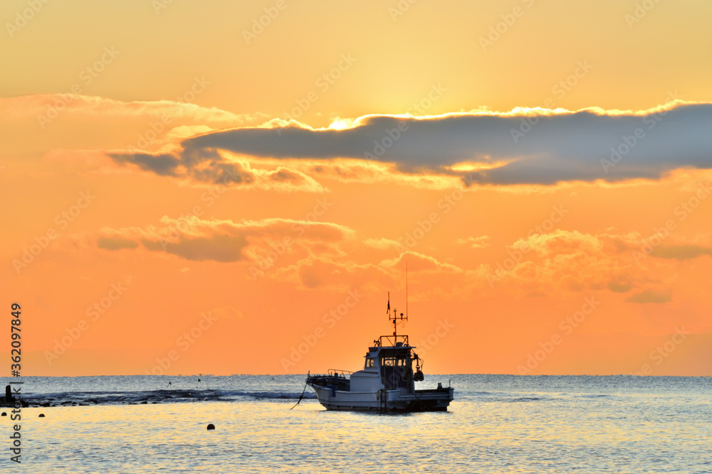 夕日が沈む材木座海岸に浮かぶ漁船