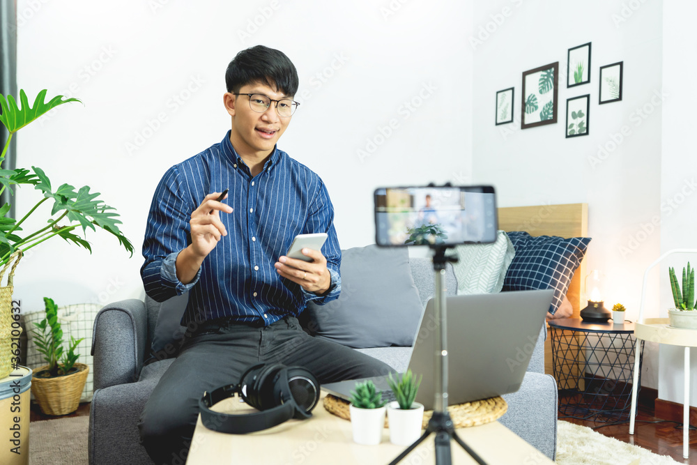 Asian blogger recording vlog video on camera review of product at home office