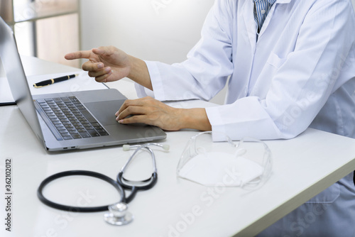 doctor working with laptop computer sitting at desk in hospital office or clinic  health care and medical technology concept.