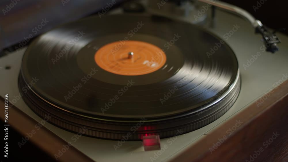 A vinyl record gets placed on a turntable and starts listening to music A vinyl record gets placed on a turntable and starts listening to music