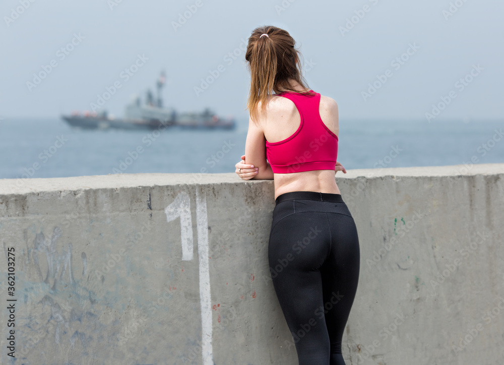 Female person observing floating military ship Female person observing floating military ship