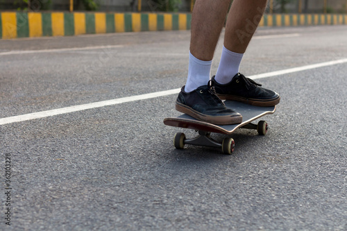Closeup shot of someone's feet who is cruising on a skateboard on an empty road. 