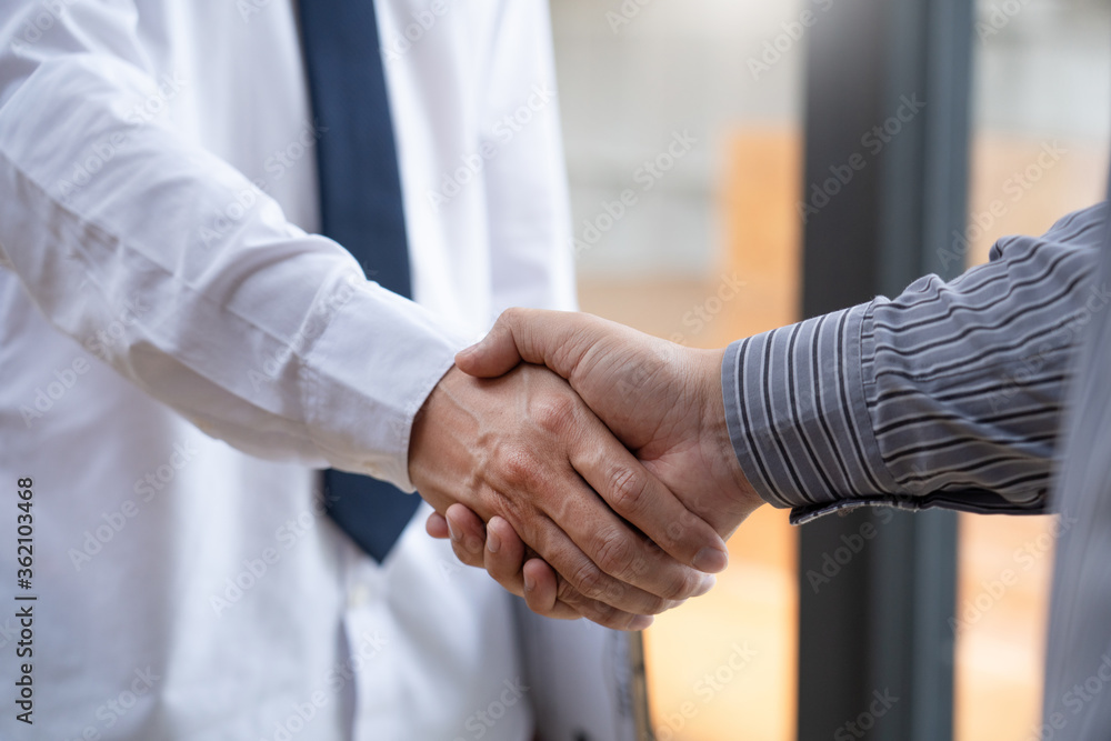 Fototapeta premium Two confident business man shaking hands during a meeting in the office, success, dealing, greeting and partner concept