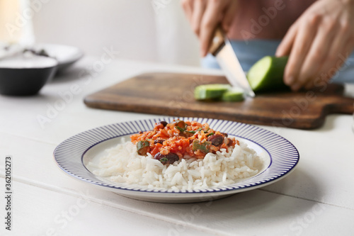 Plate with tasty rice  beans and vegetables on table