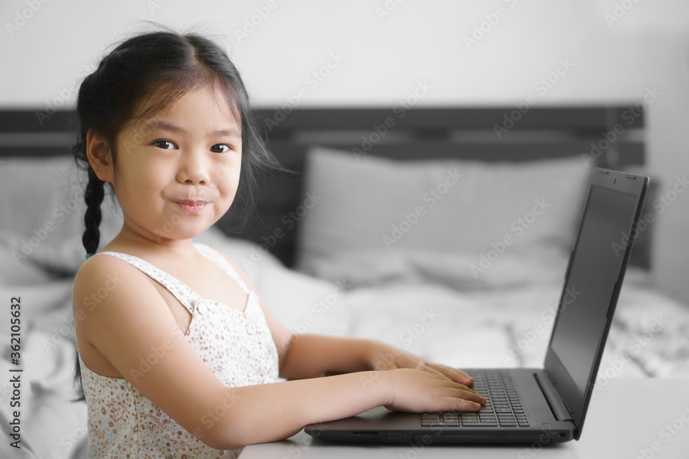 Asian child student or kid girl study online or work from home on computer notebook or play laptop by kindergarten school to primary education and happy smiling from coronavirus covid-19 and stay safe Asian child student or kid girl study online or work from home on computer notebook or play laptop by kindergarten school to primary education and happy smiling from coronavirus covid-19 and stay safe