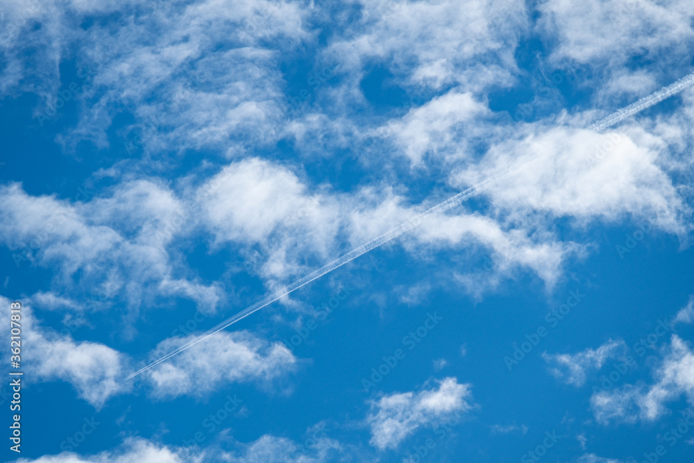 a jet plane passing through cloud filled blue sky left a long white trail behind a jet plane passing through cloud filled blue sky left a long white trail behind