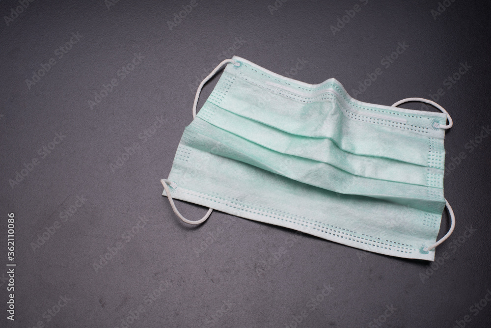A medical face mask over dark surface A medical face mask over dark surface