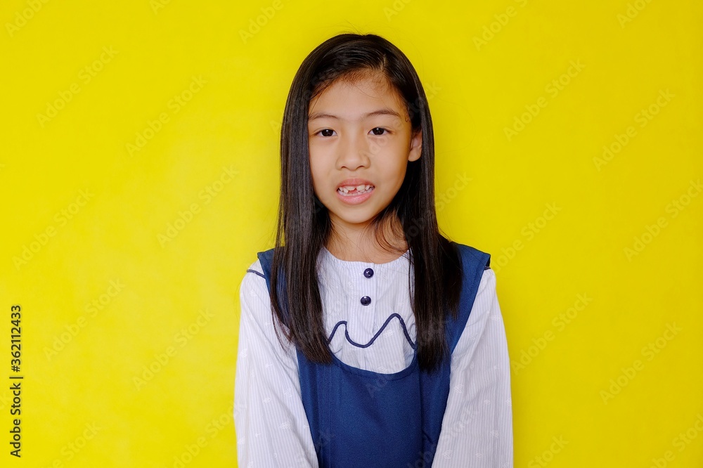 A half body shot of a bright, happy and attractive young Asian girl in white and blue school uniform with long hair, smiling. Bright yellow background. A half body shot of a bright, happy and attractive young Asian girl in white and blue school uniform with long hair, smiling. Bright yellow background.